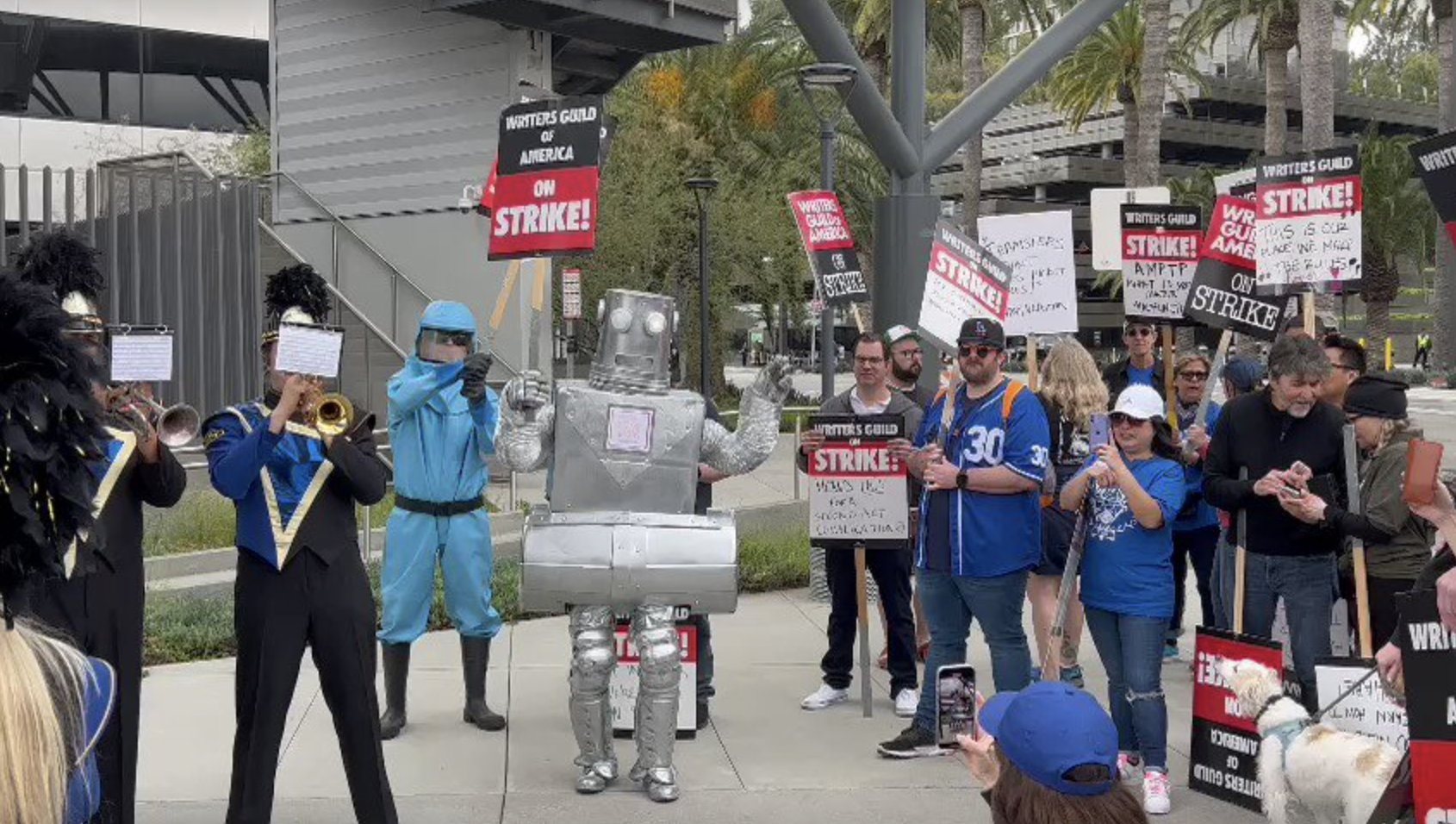 Dispatches From The Picket Lines, Day 24: Sen. Gillibrand & Colin Farrell Speak In NY; Lil Wayne Sends Burgers, A Robot Pickets & A Marching Band Plays In LA